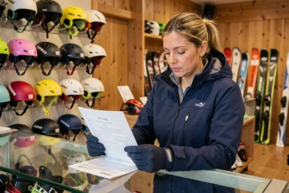 Skieuse examinant un contrat de location de matériel de ski au comptoir d'un magasin de location à Pra Loup